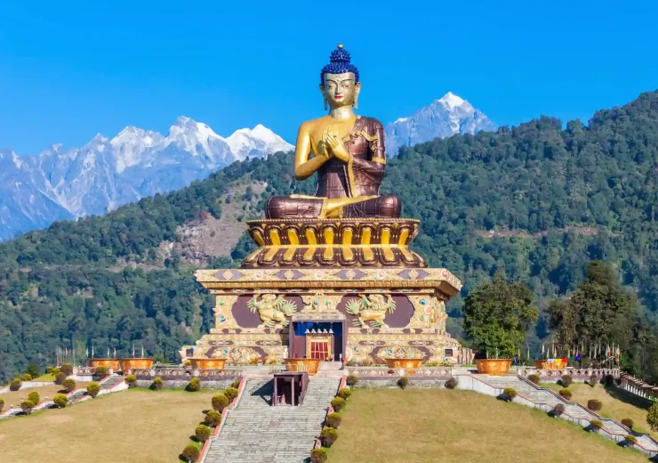 Giant Buddha statue with snow-capped Himalayan mountains in the background.